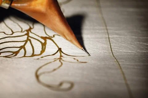 Close-up of man drawing batik pattern on fabric,focus on tjanting needle Stock Photos