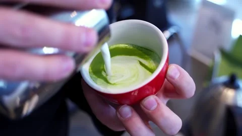 Close-up of a man drawing a heart in a red glass with matches and milk. Matcha Stock Footage 272817593