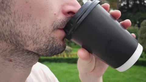 Close-up of a man drinking coffee from a black disposable cup outdoors Stock Footage 283493187