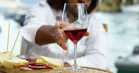 Close up of a man drinking wine and eating cheese in a habor neat the water. He Stock-Footage 154695415