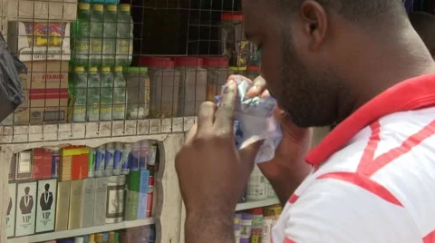 CLOSE UP: MAN DRINKS SACHET WATER AT ROADSIDE STAND Stock Footage 60627308