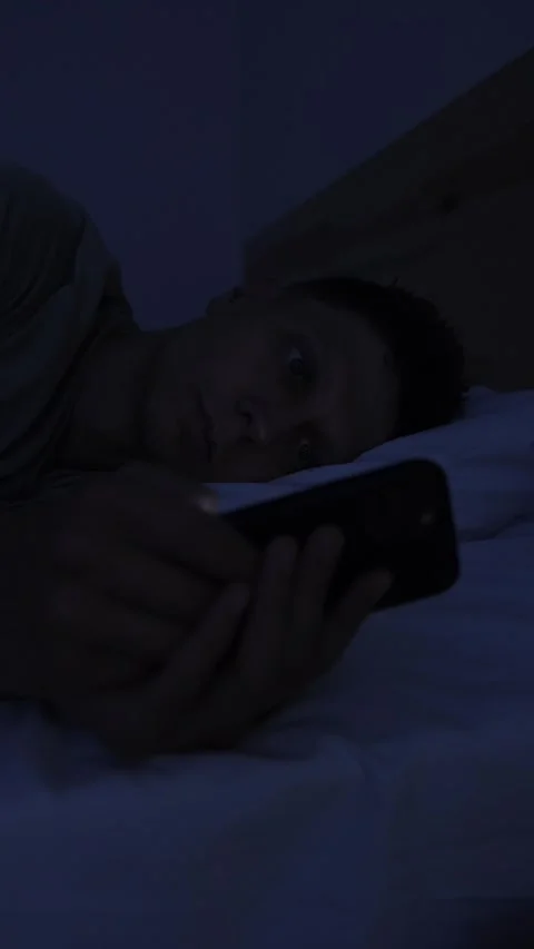Close up of man endlessly scrolling short form videos on smartphone in bed at 库存影片 346246815