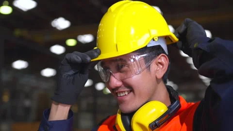 Close up man engineer wearing and adjust protective safety helmet or hard hat. Stockbeeldmateriaal 332119424