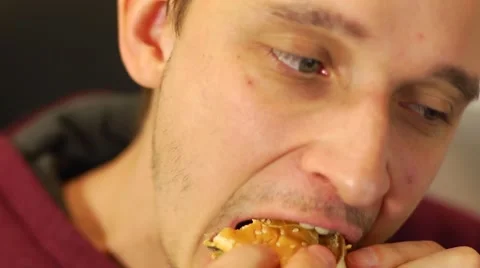 Close-up man face eating fast food hamburger working on computer in office Stock Footage 45099365