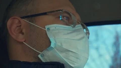 Close up of man in face mask driving car by the city street during epidemic of Stock Footage 127560125