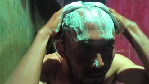 Close-up of a man facing the camera, intensely shampooing his hair. Stock Footage 321931323
