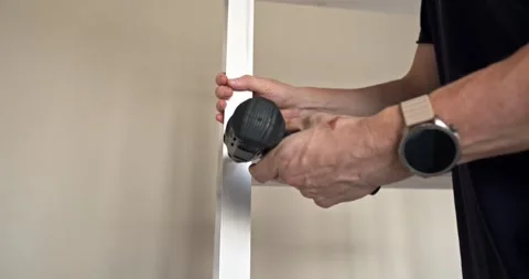 Close Up of Man Fastening Screw on Vertical Wooden Frame of White Furniture Stock Footage 314791422