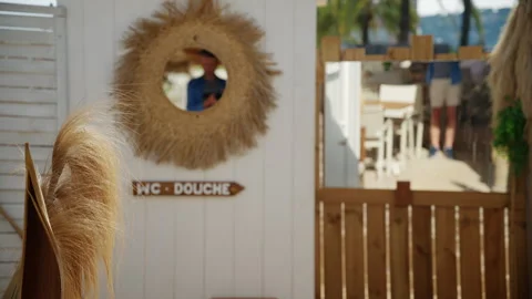 Close up of a man filming himself in a woven straw framed mirror with tropical Stock Footage 337010221