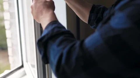 Close up of a man fixing or repairing a plastic window frame with a screwdriv Vídeo Stock 340159625