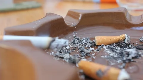 Close up of a man flicking cigarette ash into a dirty ashtray, symbolizing n 스톡 동영상 333801026