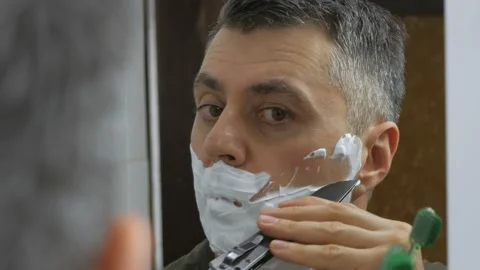 Close-up of the man in front of the mirror shaves his face with a folding knife Stock Footage 150145654