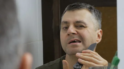 Close-up of the man in front of the mirror shaves his face with a folding knife Stock Footage 150147025