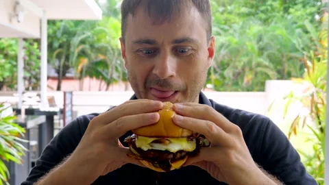 Close-up of man with funny face, licking his lips preparing to eat delicious Stock Footage 237103520