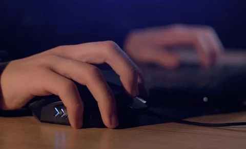 Close up of man gamer hands using computer mouse is playing video game at nig Stock Photos