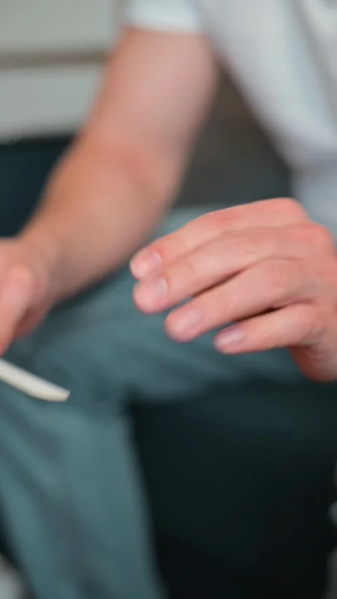 Close-up of a man getting a manicure, using a nail file to trim his fingernails Stockbeeldmateriaal 337112634