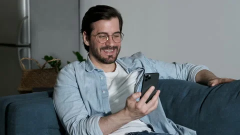 Close Up Of a man with Glasses Smiling Using a Smartphone Talking Online Stock Footage 144685394