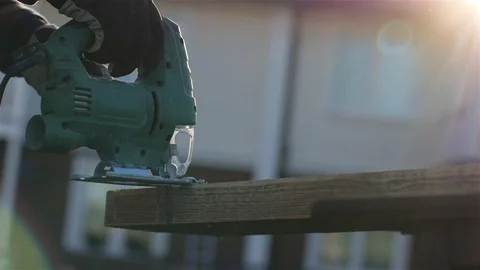 Close-up of a man in gloves with an electric jigsaw sawing a plank in the yard Stock-Footage 111469084