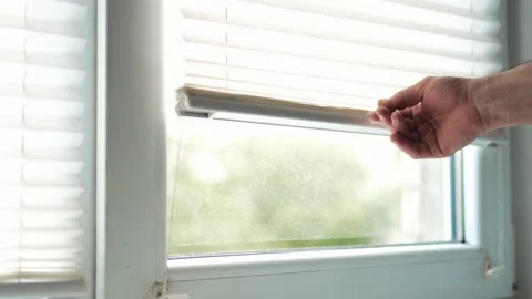Close up of a man hand adjusting white pleated window blinds to control day.. Vídeo Stock 340159349
