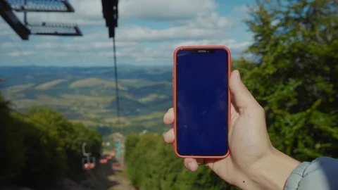 Close up man hand hold phone with vertical screen on a lift in the mountains at Stock Footage 116998448