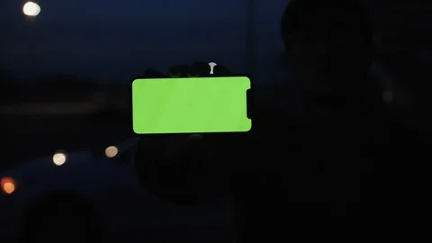 Close up man hand holding smartphone with horizontal green screen on night city Stock Footage 108394722