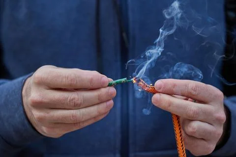 Close up of man hand lighting up a firecrackers with wick Stock Photos