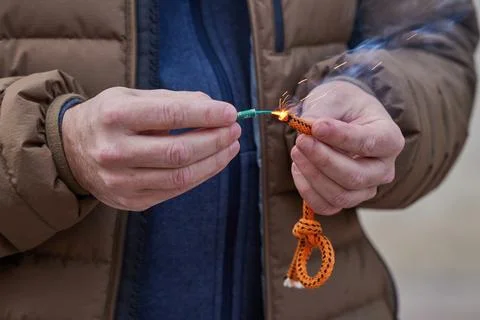 Close up of man hand lighting up a firecrackers with wick Stock Photos