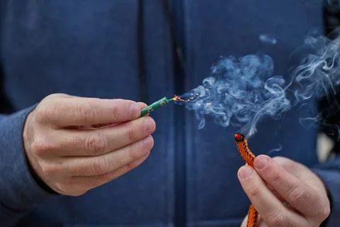 Close up of man hand lighting up a firecrackers with wick Stock Photos