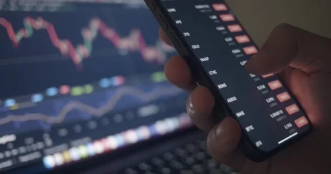 Close-up man hand with mobile phone and laptop with financial analysis charts Stock Footage 264325145