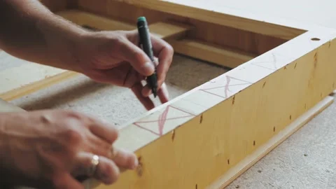 Close-up of man hand notices the length of the wooden square and draws a short Stock-Footage 233089864