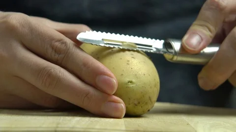Close Up Man Hand Peeling Potato with Peeler in Studio Stock Footage 76521935