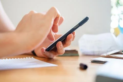 Close-up of a man hand with phone using calculator to count money. Finance Stock Photos