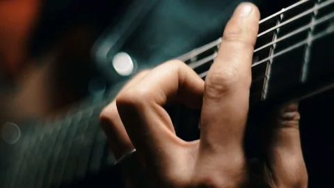 Close up of a man hand playing a guitar picking strings. Slow motion Video stock 77487378