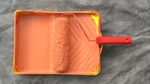 Close up of man hand preparing orange paint on tray with roller. Home DIY. Stock Footage 133530052