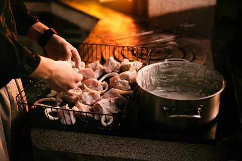 Close-up man hand putting big tasty juice raw t-bone beaf steak on grill at b Stock Photos
