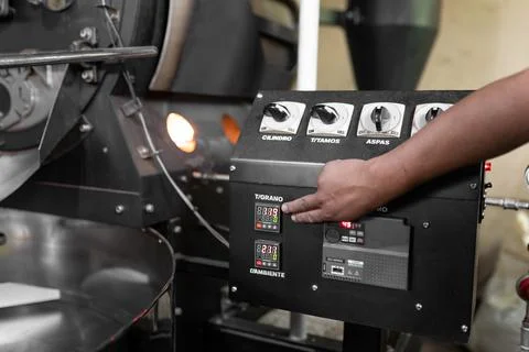 Close up of a man hand setting the buttons of a coffee roaster machine Stock Photos