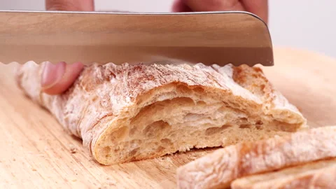 Close-up man hand slicing or cutting fresh brown bread with bread knife Stock Footage 170602470