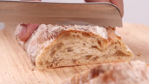 Close-up man hand slicing or cutting fresh brown bread with bread knife Stock Footage 170602922