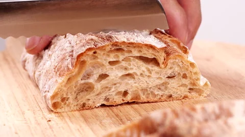 Close-up man hand slicing or cutting fresh brown bread with bread knife Stock Footage 170603083