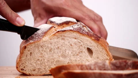 Close-up man hand slicing or cutting fresh brown bread with bread knife Stock Footage 170605155