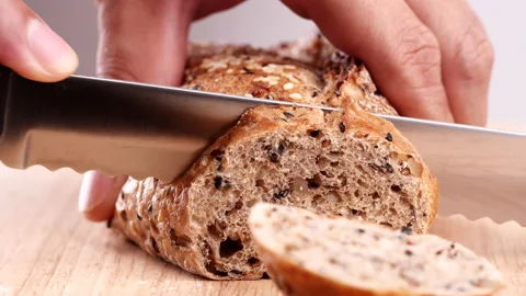 Close-up man hand slicing or cutting fresh brown bread with bread knife Stock Footage 170605959