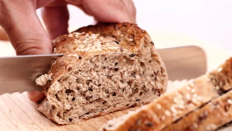 Close-up man hand slicing or cutting fresh brown bread with bread knife Stock Footage 170612816