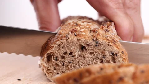 Close-up man hand slicing or cutting fresh brown bread with bread knife Stock Footage 170612911