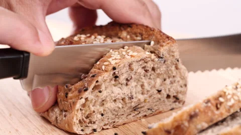 Close-up man hand slicing or cutting fresh brown bread with bread knife Stock Footage 170612955