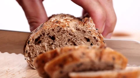 Close-up man hand slicing or cutting fresh brown bread with bread knife Stock Footage 170613057