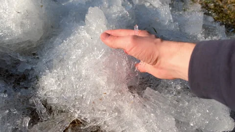 Close-up man hand touching broken ice crystals on the land in spring day. Stock Footage 311861494
