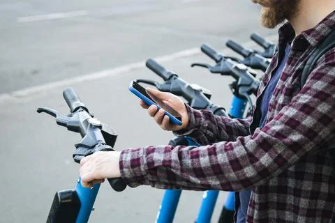 Close up of man hand using mobile app for rental electric scooter. Stock Photos