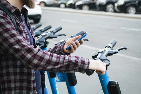 Close up of man hand using mobile app for rental electric scooter. Stock Photos