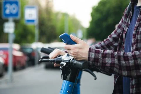 Close up of man hand using mobile app for rental electric scooter. Foto stock