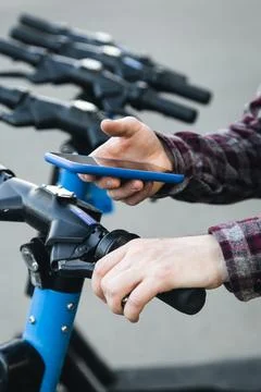 Close up of man hand using mobile app for rental electric scooter. Foto stock