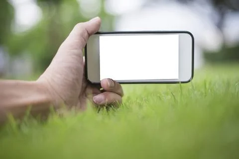 Close up man hand using smartphone in green park, Mockup of blank screen of.. Stock Photos